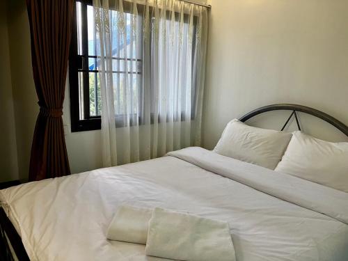 a bedroom with a white bed with a window at บ้านพักสำหรับ 10 ท่าน in Udon Thani