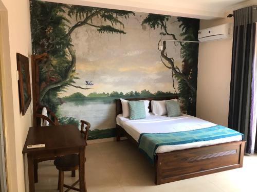 モラトゥワにあるAmani Lake Resortの壁に絵画が描かれたベッド付きの部屋