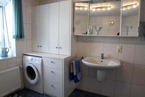 a bathroom with a sink and a washing machine at Elisa Ferienwohnung in Wadern