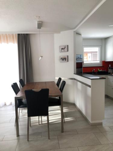 una cucina e una sala da pranzo con tavolo e sedie in legno di Seebach B1 a Arosa