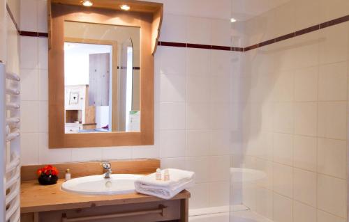 uma casa de banho com um lavatório, um espelho e um chuveiro em Résidence Labellemontagne Rochebrune LE VALLON**** em Orcières
