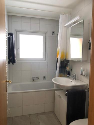 ein Badezimmer mit einer Badewanne, einem Waschbecken und einem Badetubermott in der Unterkunft Seebach B1 in Arosa