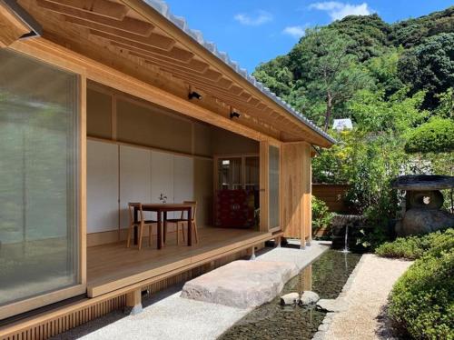 una casa con un porche de madera con una mesa. en 萌蘖　露天風呂とサウナがある現代の湯治場 en Kagoshima