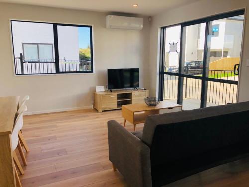 a living room with a couch and a flat screen tv at Modern & Luxurious Home 3 in Auckland