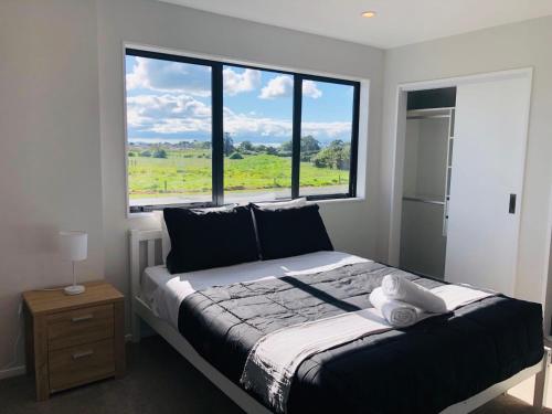 a bedroom with a bed with a large window at Modern & Luxurious Home 3 in Auckland