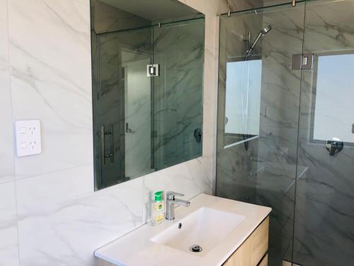 a bathroom with a sink and a shower at Modern & Luxurious Home 3 in Auckland