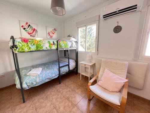 1 Schlafzimmer mit 2 Etagenbetten und einem Stuhl in der Unterkunft El N5 Casa en Rincon de la Victoria Golf & Piscina in Rincón de la Victoria