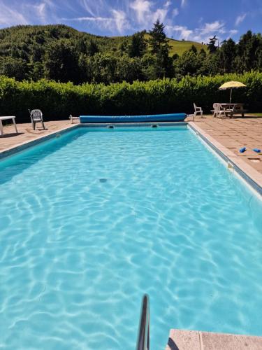 a large blue swimming pool with chairs and an umbrella at Glamping Hut - Riverview 5 in Garthbeibio