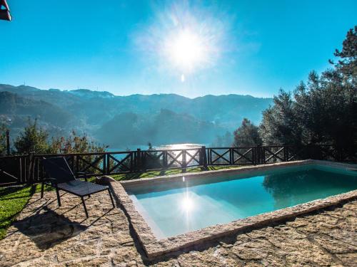 a pool with a chair and a view of the mountains at Casa da Terra Nova - Gerês in Rio Caldo