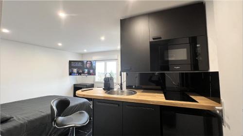 een kamer met een keuken met een wastafel en een magnetron bij Bella vita - Studio tout équipé - Tv Netflix - centre ville 100m- Gare 50m - Basilique 200m in Lisieux