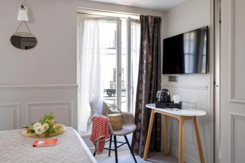 a bedroom with a bed and a table and a window at Hôtel Madeleine Haussmann in Paris