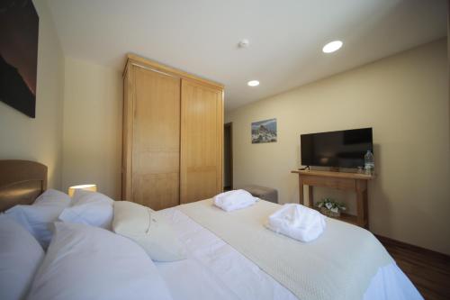 a bedroom with two beds with white sheets and a television at Casa da Fonte - Gerês in Geres
