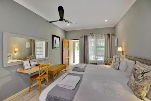 a bedroom with a large white bed and a desk at River View Lodge in Kasane