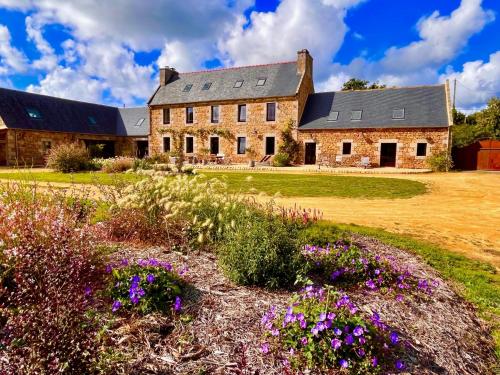 ein großes Steinhaus mit Blumen im Vordergrund in der Unterkunft Les Villas d Onalou Kergastel in Penvénan