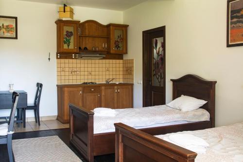 a bedroom with two beds and a table and a kitchen at Pension Andra's House in Horezu
