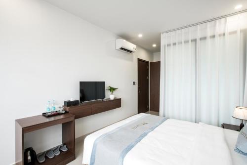 a white bedroom with a bed and a television at AUI Hotel 38 Máy Tơ in Ðoan Xá