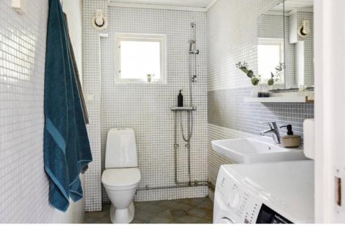 Baño blanco con aseo y lavamanos en Cosy house in the archipelago, en Värmdö