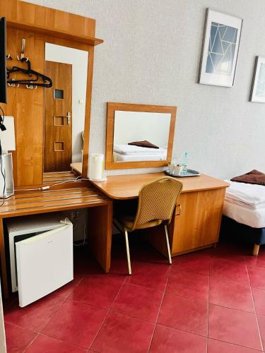 a bedroom with a desk with a bed and a mirror at Hotel Elda in Bydgoszcz