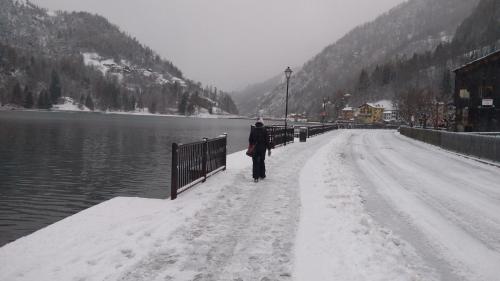a man walking down a snow covered road next to a lake at Appartamento a 2,5 km da Alleghe in Alleghe