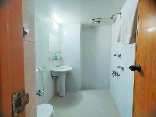 a white bathroom with a sink and a toilet at Hotel Supreme in Sylhet