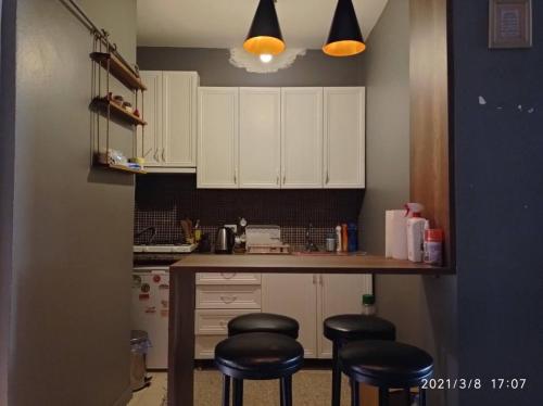 a kitchen with white cabinets and black stools at Beşiktaş Meydan in Istanbul