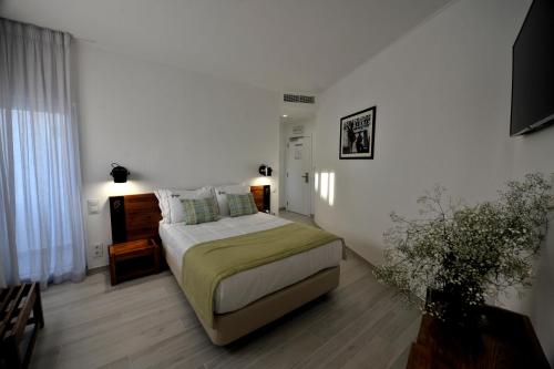 a bedroom with a bed in a white room at Hotel Búzio in Sines