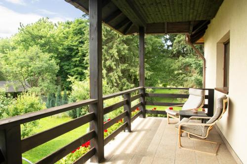 a porch with two chairs and a table and a fence at Pension Andra's House in Horezu