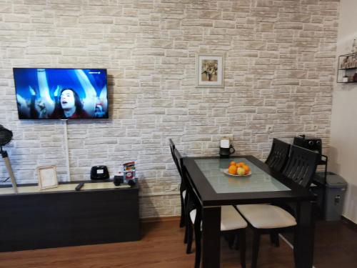 uma sala de jantar com uma mesa e uma televisão numa parede de tijolos em Студио 836 em Bansko