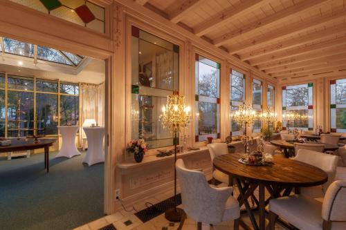 una sala da pranzo con tavoli, sedie e finestre di Villa-Ottilienruh-Ottilien-Suite a Ilsenburg