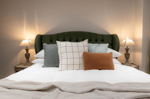 a bed with a green headboard and pillows on it at Three Bedroom Apartments near Spitalfields Market and Tube Station in London