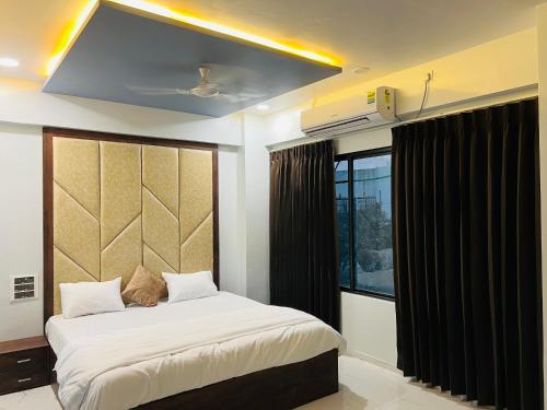 ein Schlafzimmer mit einem großen Bett und einem Fenster in der Unterkunft Hotel New City Light in Surat