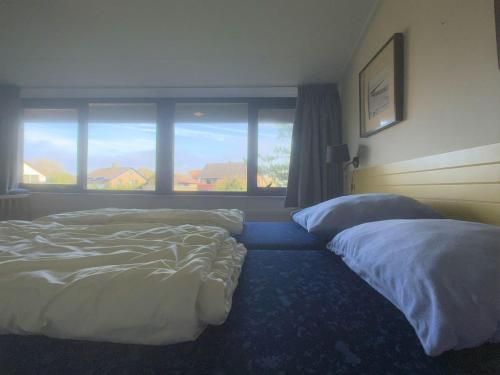 a bedroom with two beds and a large window at Wijk de Brabander 59 in Cadzand