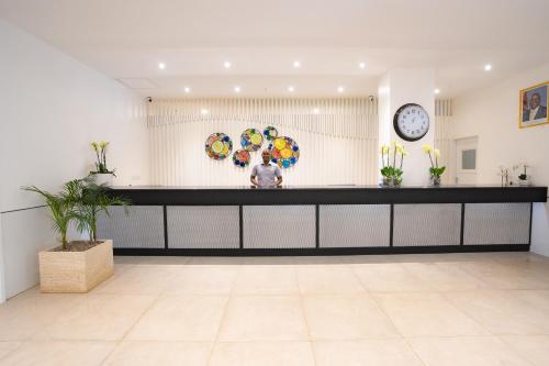 a lobby with a counter with a clock on the wall at Sarova Imperial Hotel in Kisumu