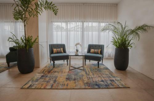 two chairs and a table in a room with plants at Sarova Imperial Hotel in Kisumu