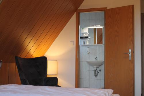ein Schlafzimmer mit einem Bett, einem Waschbecken und einem Stuhl in der Unterkunft Träbeser Bauernstube in Meiningen