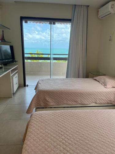 a bedroom with two beds and a view of the ocean at Casa na praia em condomínio de luxo - Porto Brasil Resort in Parnamirim