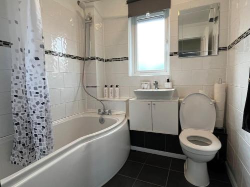 a bathroom with a tub and a toilet and a sink at Spacious home near Glasgow Green in Glasgow