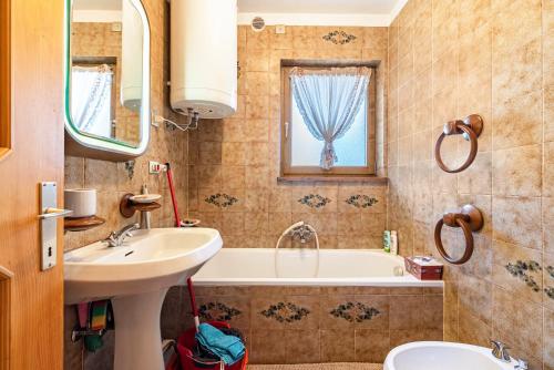 a bathroom with a sink and a tub and a toilet at Ciasa Apelli in Pozza di Fassa