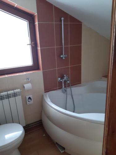 a bathroom with a white tub and a toilet at Cisówka Pokoje Gościnne in Piwniczna