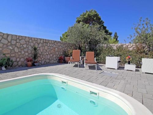 a swimming pool with chairs and a stone wall at Villa Vanda in Dubrovnik