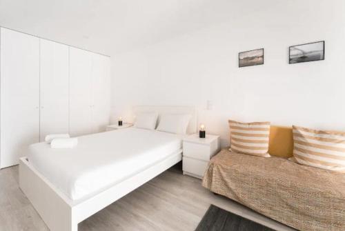 ein weißes Schlafzimmer mit 2 Betten und einem Sofa in der Unterkunft OPO - Fantastic studio with garden in Porto