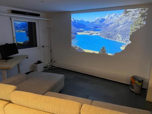 uma sala de estar com uma grande televisão pendurada na parede em SmartHome Top of the World em St. Moritz