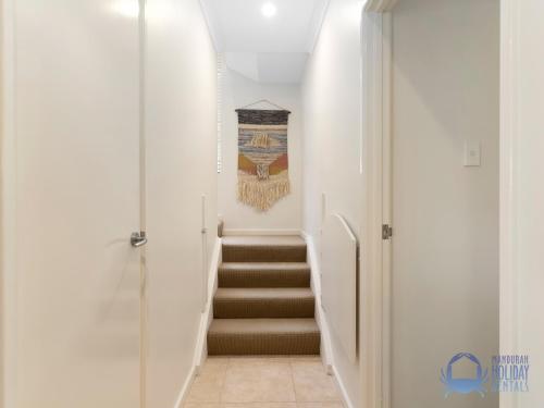 a hallway with stairs with a painting on the wall at Summer Breeze at Avalon Beach in Wannanup