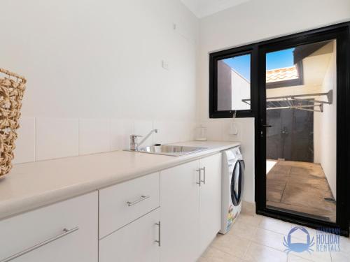 a white kitchen with a sink and a dishwasher at Summer Breeze at Avalon Beach in Wannanup
