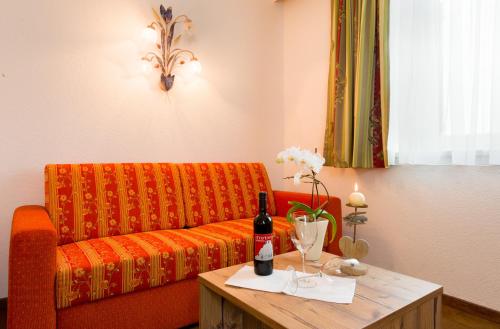 an orange couch with a table with a bottle of wine at Hotel Gasthof Zum Schwanen in Reutte