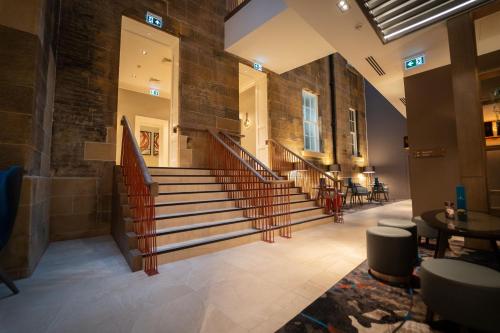 a lobby of a building with stairs and tables at Clayton Hotel Glasgow City in Glasgow