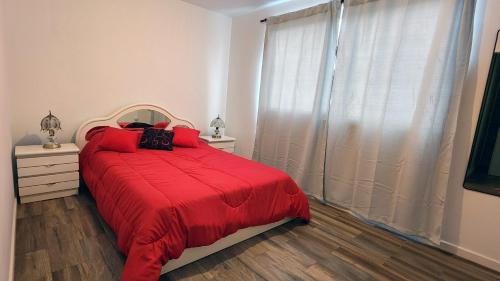 - une chambre avec un lit doté d'une couverture rouge et d'une fenêtre dans l'établissement Departamento con cochera Mar del Plata, à Mar del Plata