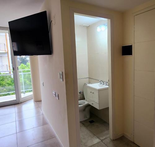 a bathroom with a toilet and a tv on the wall at Departamento con cochera Mar del Plata in Mar del Plata