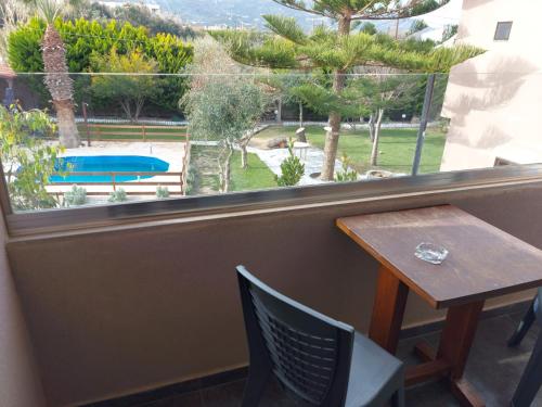un tavolo con sedie e una finestra con vista sulla piscina di The Santo George Beach Resort ad Amoudara Herakliou
