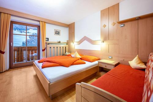 a bedroom with two beds with orange pillows and a window at Niederkoflhof Klausberg in Cadipietra